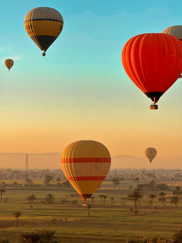 Hot air balloons soaring over Luxor's stunning scenery at sunrise, offering breathtaking views.